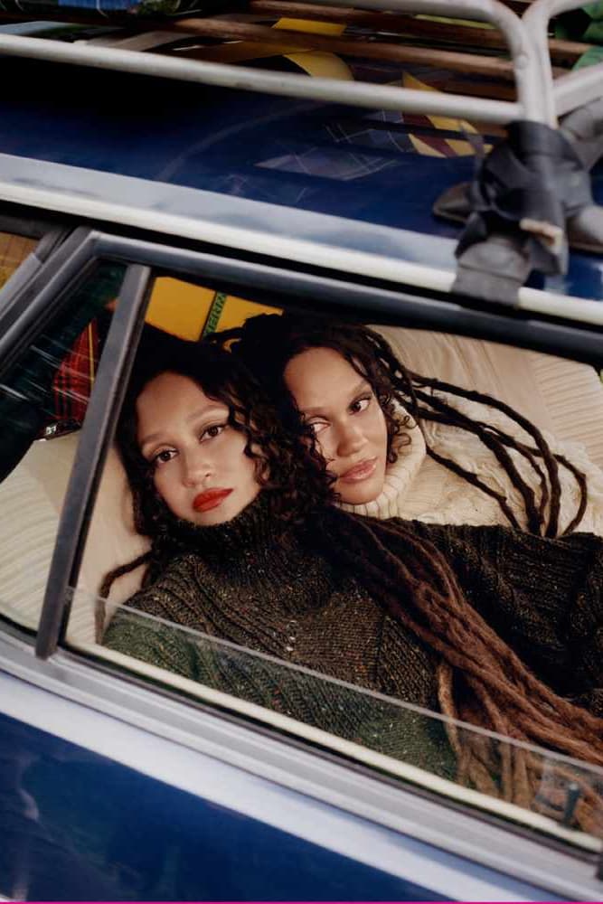 two twins posing together in grassy forest sharing a coat, byredo holiday, fragrance, makeup, perfume 